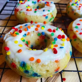 close up of funfetti donut with white icing and rainbow sprinkles on top