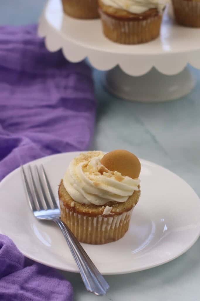 A treat on the plate with a vanilla wafer on top.