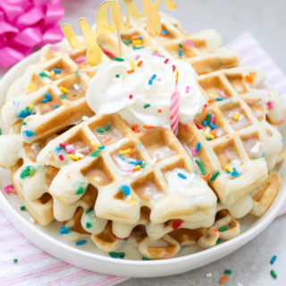 Stack of two funfetti waffles with cool whip and rainbow sprinkles on top