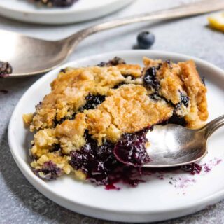 plate of blueberry dump cake with gooey filling and golden brown crust