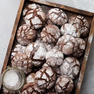 Chocolate crinkle cookies on a wooden tray with powdered sugar on top
