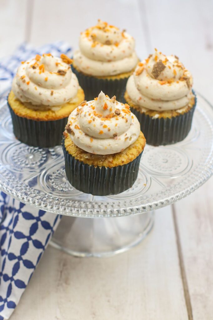 Butterfinger Cupcakes sprinkled with crushed butterfinger on a cake stand