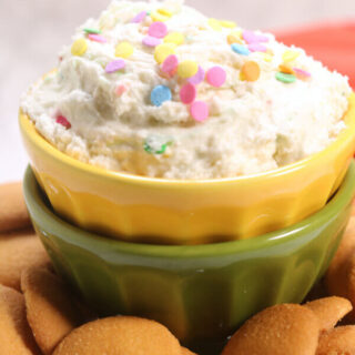 bowl of confetti cake batter dip with colorful sprinkles on top, surrounded by nilla cookies
