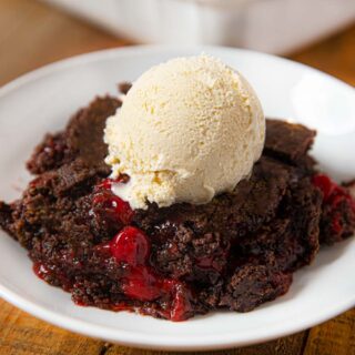 plate of cherry chocolate dump cake with a scoop of vanilla ice cream on top