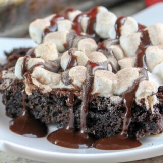 plate of hot chocolate dump cake toped with tiny marshmallows and fudge drizzle