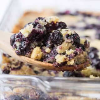 casserole dish of lemon blueberry dump cake with a spoon full taken out