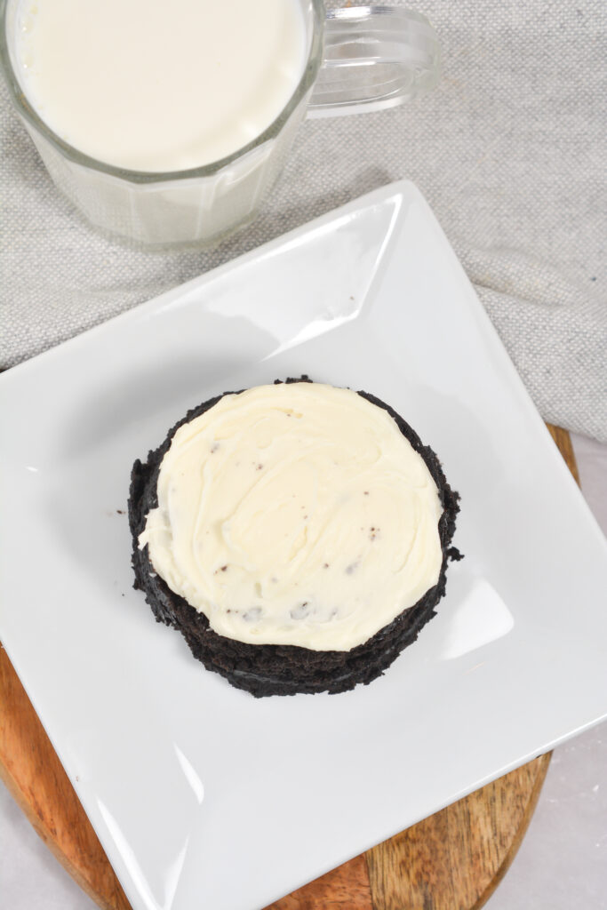 overhead view of oreo microwave cake on a white plate with a glass of milk in the background