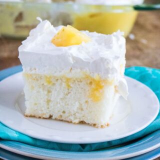 a slice of pina colada cake on a white plate on a blue cloth on 2 blue plates