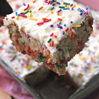 piece of vanilla funfetti cake with white icing and rainbow sprinkles on top