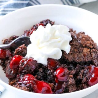 bowl of chocolate cherry dump cake with cool whip on top