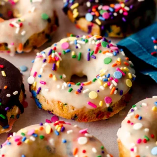 various funfetti donuts with chocolate and white icing, with rainbow sprinkles on top