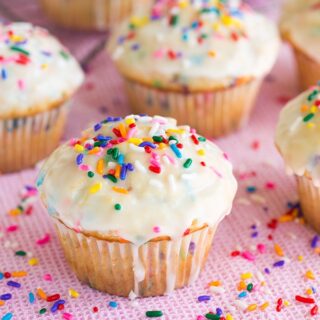 multiple funfetti muffins with white glaze and rainbow sprinkles on top