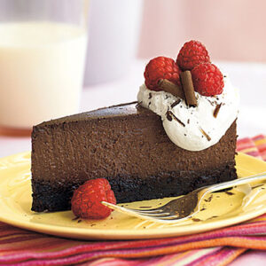 raspberry-chocolate truffle cheesecake with wiped cream and fresh raspberries on top