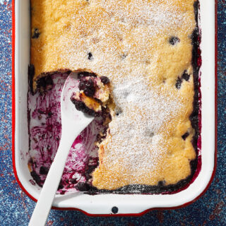 casserole dish of golden brown crusted lemon-blueberry dump cake with powdered sugar on top