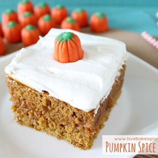 pumpkin poke cake with white frosting and a candy corn pumpkin on top