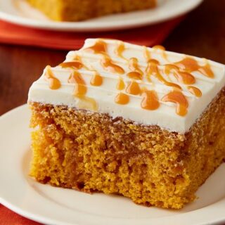 pumpkin Caramel poke cake with white frosting and caramel dots on top