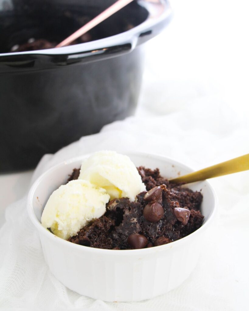 Chocolate Lava Cake in a Crock Pot in a bowl topped with ice cream with the crock pot in the background