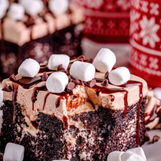 hot chocolate poke cake with tiny marshmallows and chocolate drizzle on top