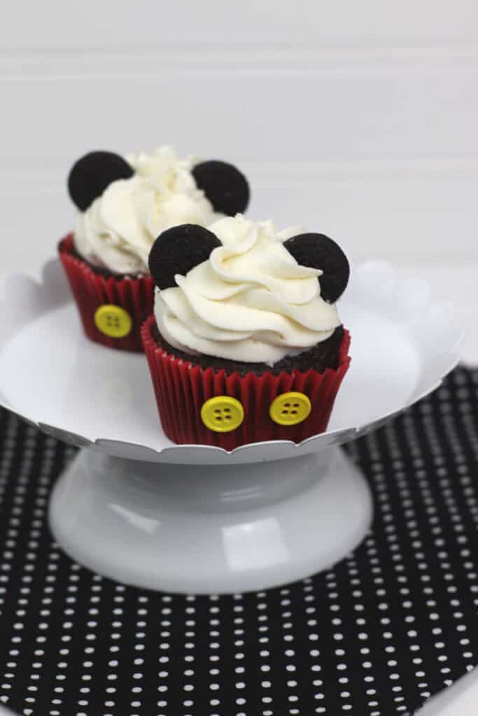 Two mickey cupcakes on a white platter.
