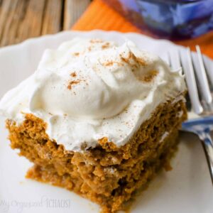pumpkin poke cake with white frosting and cinnamon sprinkled on top
