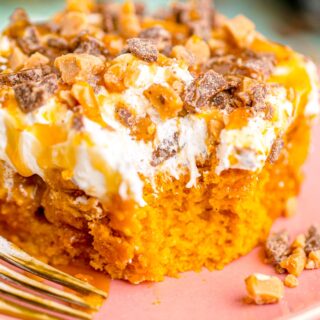 pumpkin poke cake with white frosting, caramel drizzle and toffee bits on top