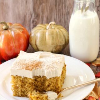 pumpkin poke cake with frosting and sprinkled cinnamon on top