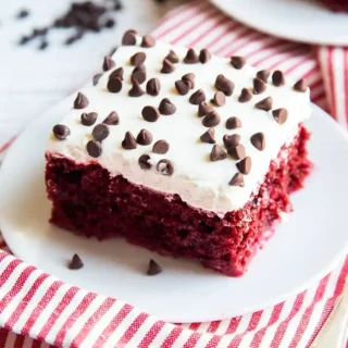 red velvet poke cake with white frosting and chocolate chips on top