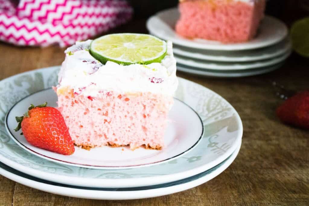 A slice of the strawberry margarita cake with a slice of lime on top.
