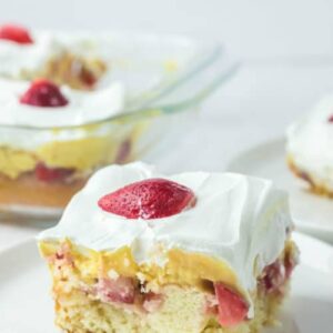 strawberry poke cake with vanilla pudding and a fresh strawberry slice on top