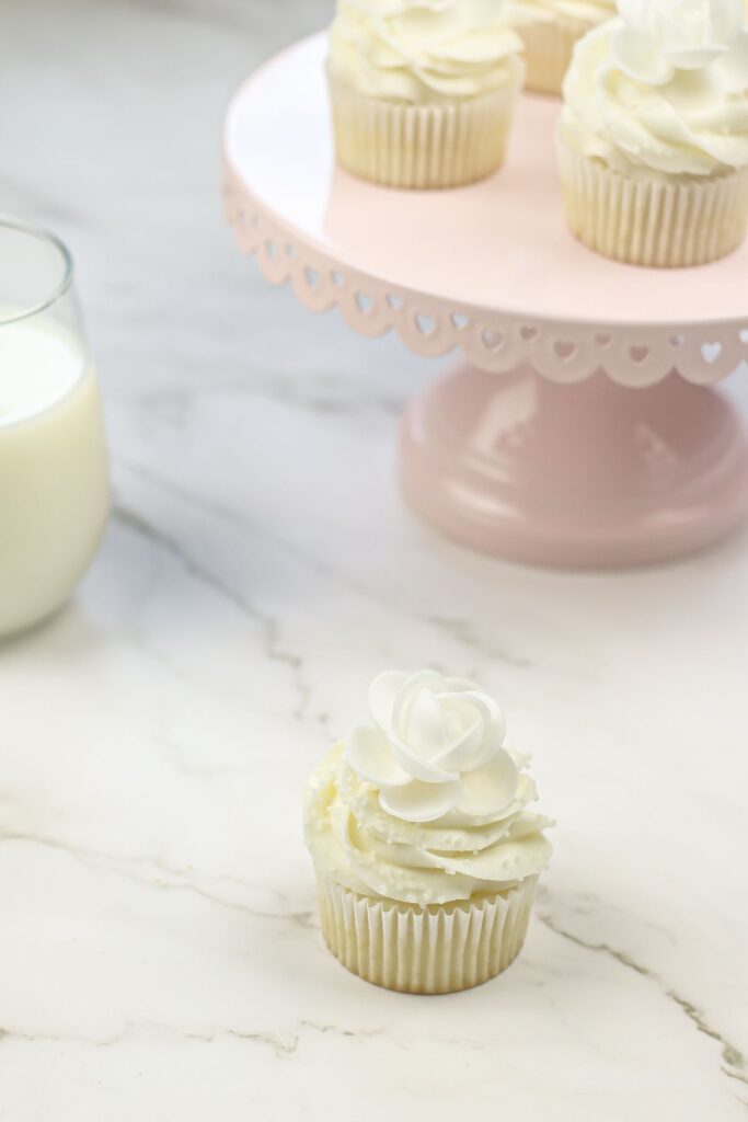 White Wedding Cupcakes on a counter and on a cake stand.