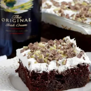 baileys chocolate poke cake with white frosting and mint chocolate crumbles on top