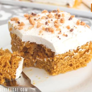 pumpkin poke cake with white frosting and nuts on top