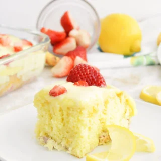 lemon strawberry poke cake with fresh strawberry slices and a lemon slice