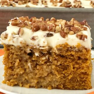 pumpkin pie poke cake with white frosting and nuts on top