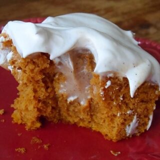 pumpkin vanilla custard poke cake with white frosting on top