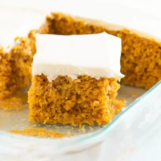 pumpkin poke cake with white frosting on top
