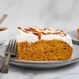 pumpkin poke cake with white frosting and caramel drizzle on top