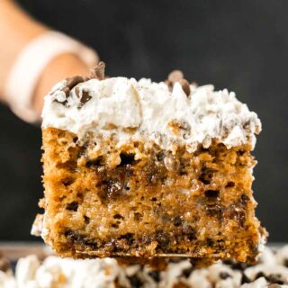 chocolate chip pumpkin poke cake with white frosting on top