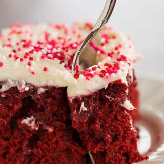 red velvet poke cake with white frosting and pink sprinkles on top