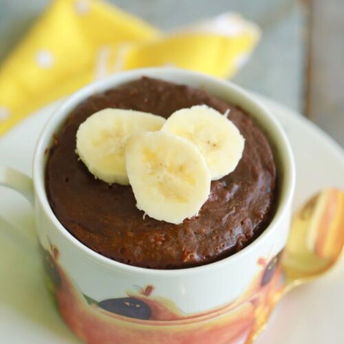 chocolate banana mug cake in a mug with fresh banana slices on top