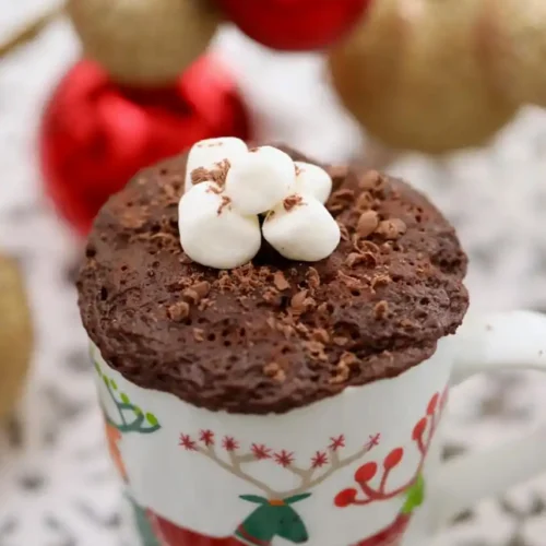 a chirstmas mug filled with egg free hot chocolate mug cake and topped with mini marshmallows
