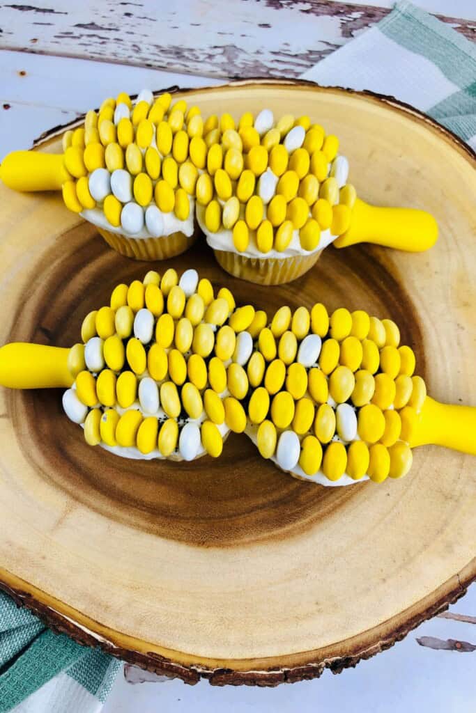 Four cupcakes on a platter with corn holders.