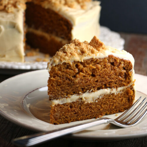 pumpkin spice cake with white frosting on top and in the middle and nuts on top