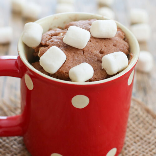a red mug filled with hot chocolate mug cake and topped with fluffy white mini marshmallows