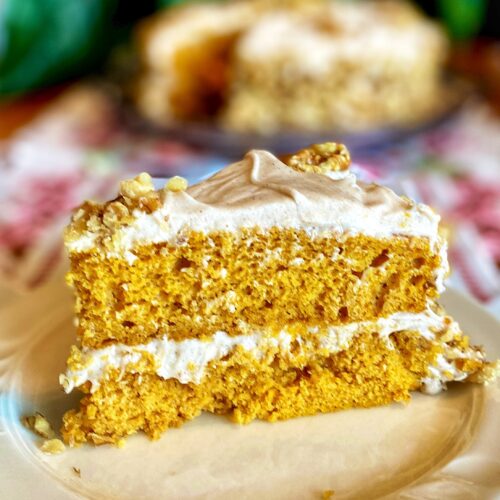 pumpkin cake with white frosting on top and in the middle, with nuts on top