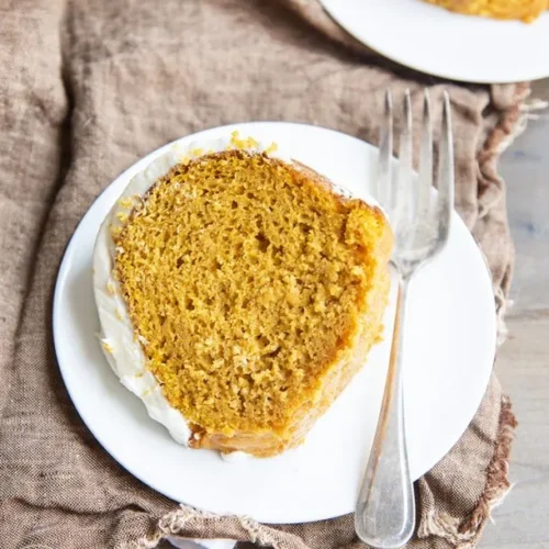 pumpkin cake slice on a white plate with a fork next to it