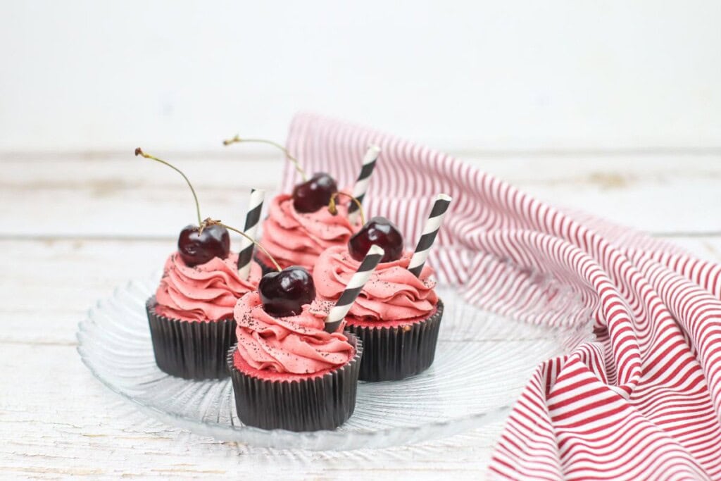 4 black cherry cupcakes on a plate.