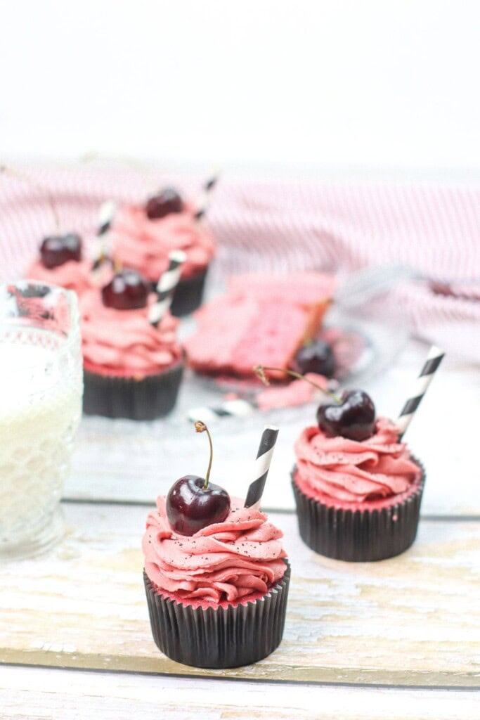 A close up of the cherry cupcakes dessert with straws in them.