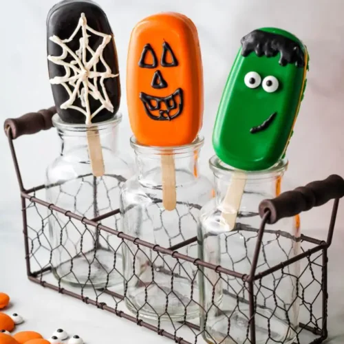 Various cakesicles including a spider web, pumpkin and Frankenstein