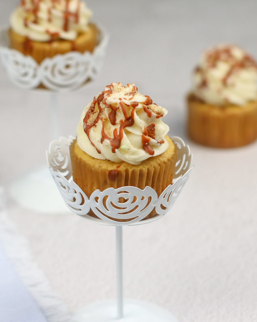 Cinnamon Cupcake on a cupcake stand with more cupcakes in the background.